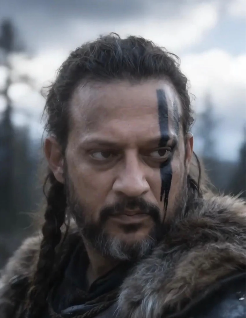 Sean, with dark braided hair, a beard and a narrow mark over his left eye